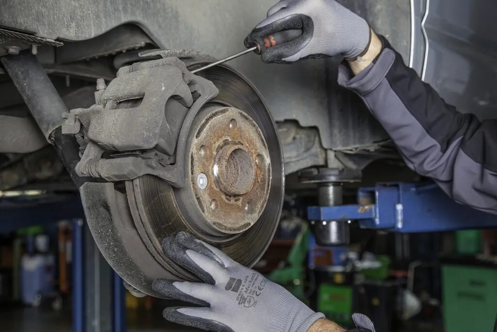 A mechanic in gloves working on a brake disc