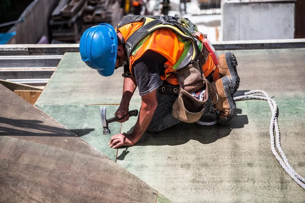 A roofer in a hard hat nailing down a roof